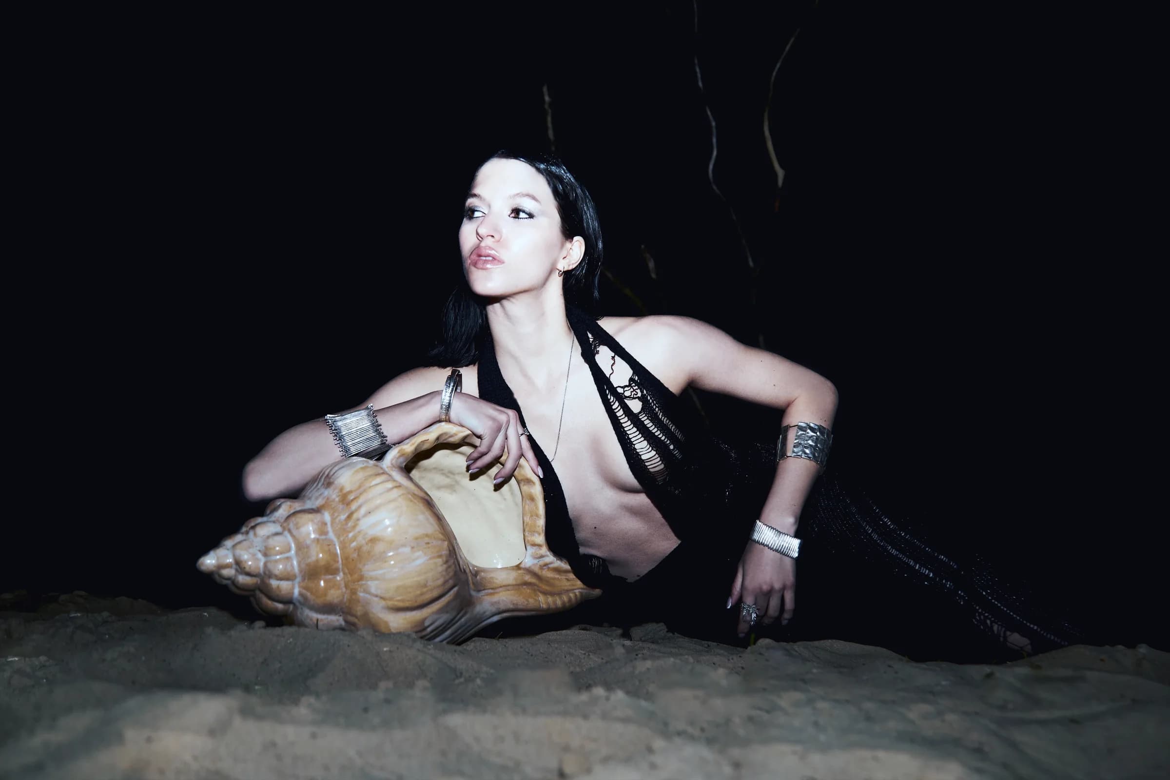 A dark-clad model posed with an oversized shell