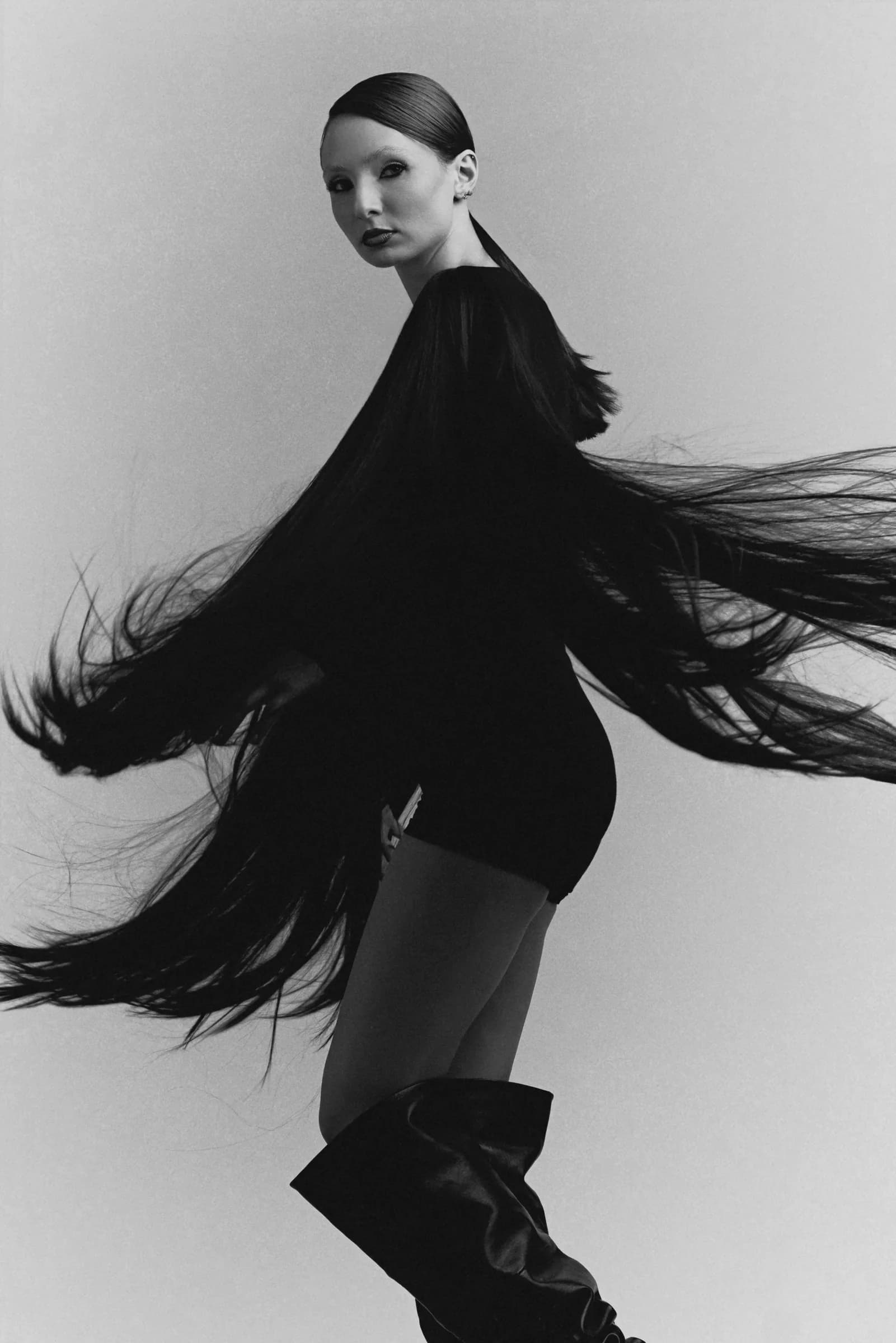 Monochrome fashion portrait with a black fringed garment in motion